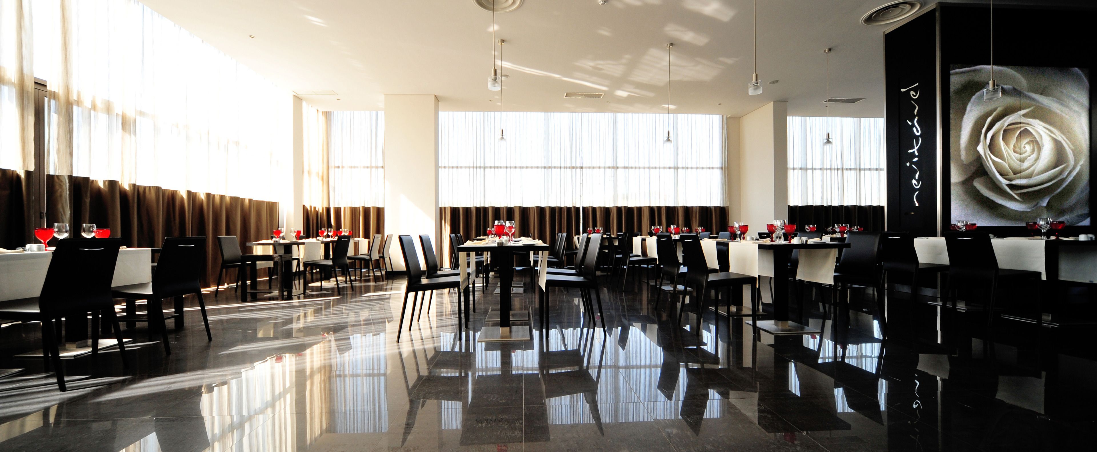 Un restaurante espacioso y moderno con suelo pulido, ventanas amplias y una decoración minimalista.
