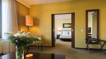 A hotel room with a bed, bedside table, lamp, chair, and a mirror.