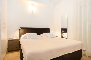Un dormitorio moderno con una cama grande, mesitas de noche y un espejo.