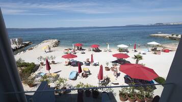 A beach with red umbrellas and lounge chairs.