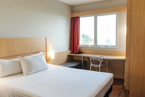 A hotel room with a bed, a desk, a chair, and a window with curtains. - Aera São José Floripa (Sao Jose)