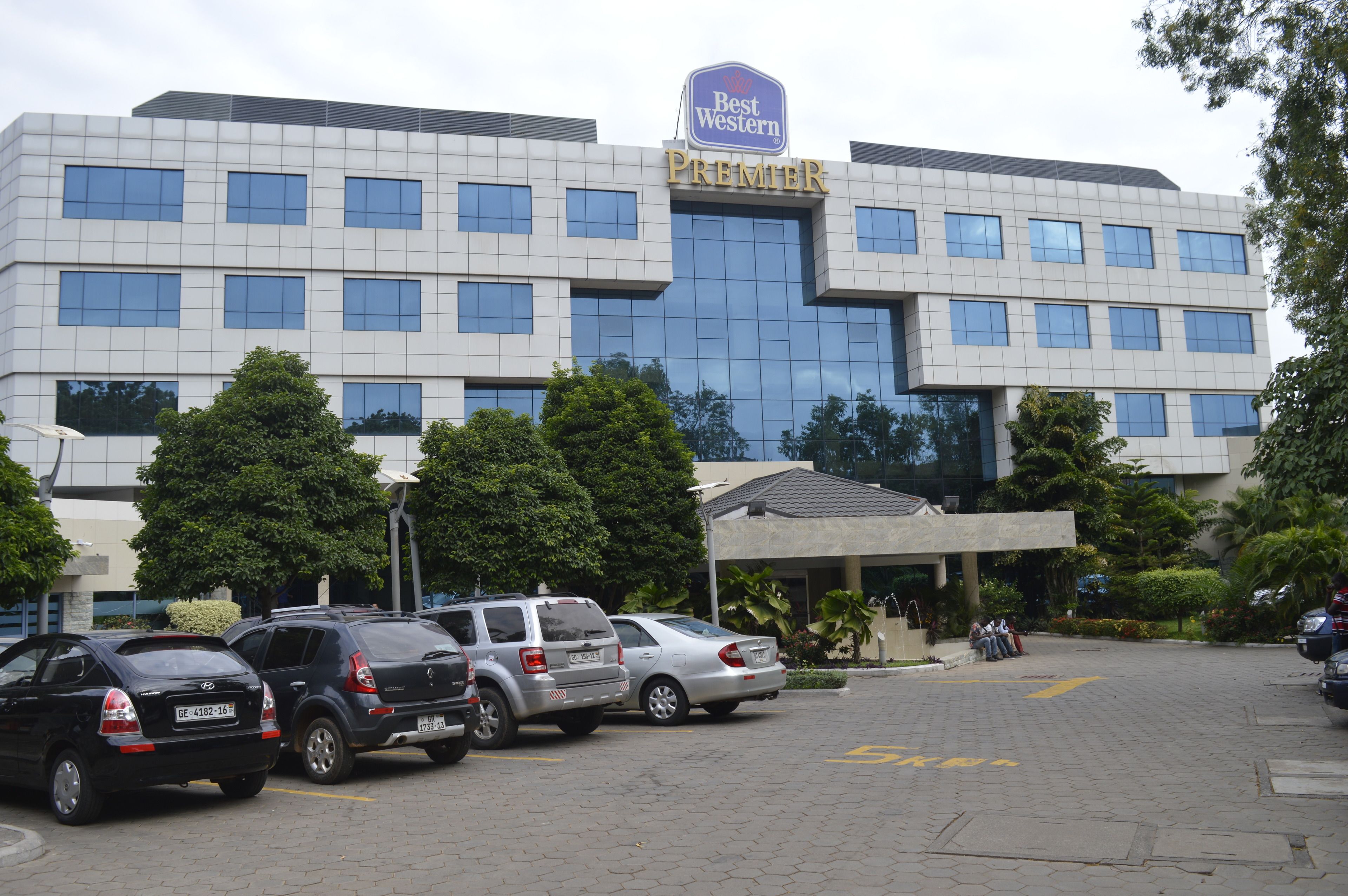 A Best Western Premier hotel with a modern facade, multiple floors, and a parking lot with several cars.