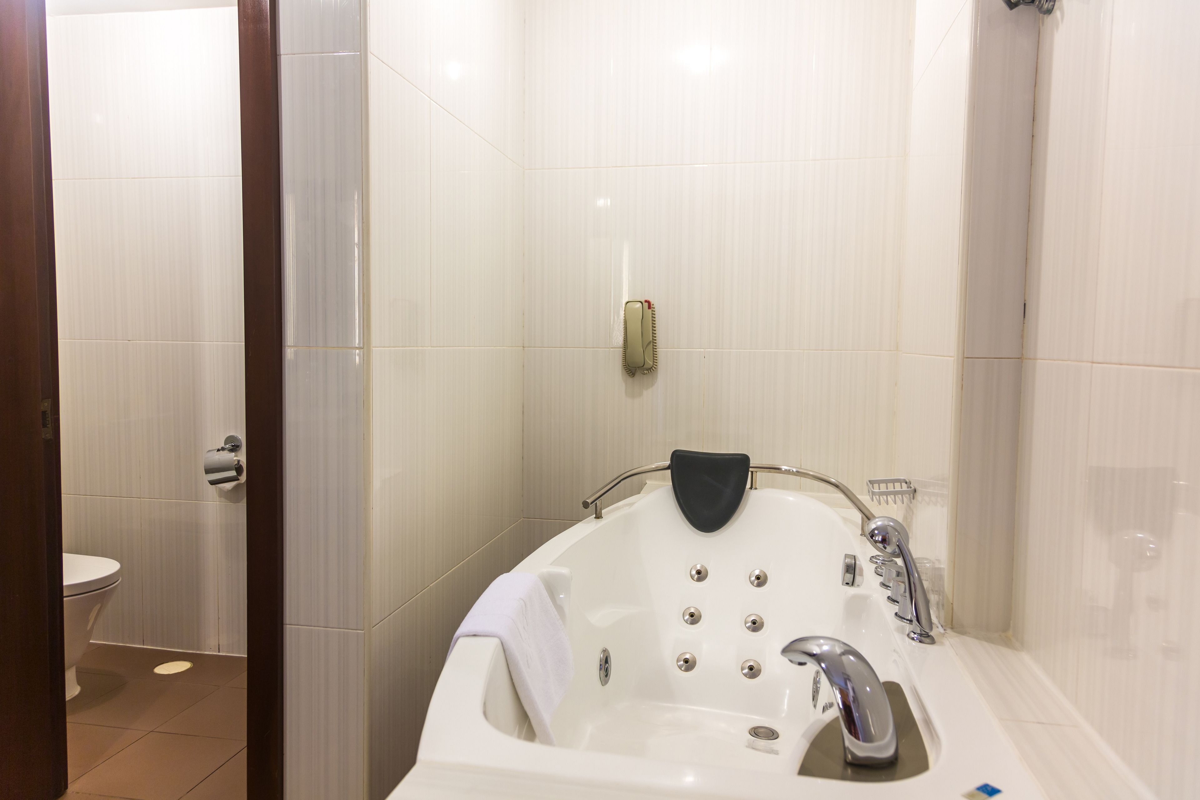 A bathroom with a white bathtub, a toilet, and a shower area.