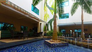 An indoor pool area with a blue mosaic floor, palm trees, and seating areas.