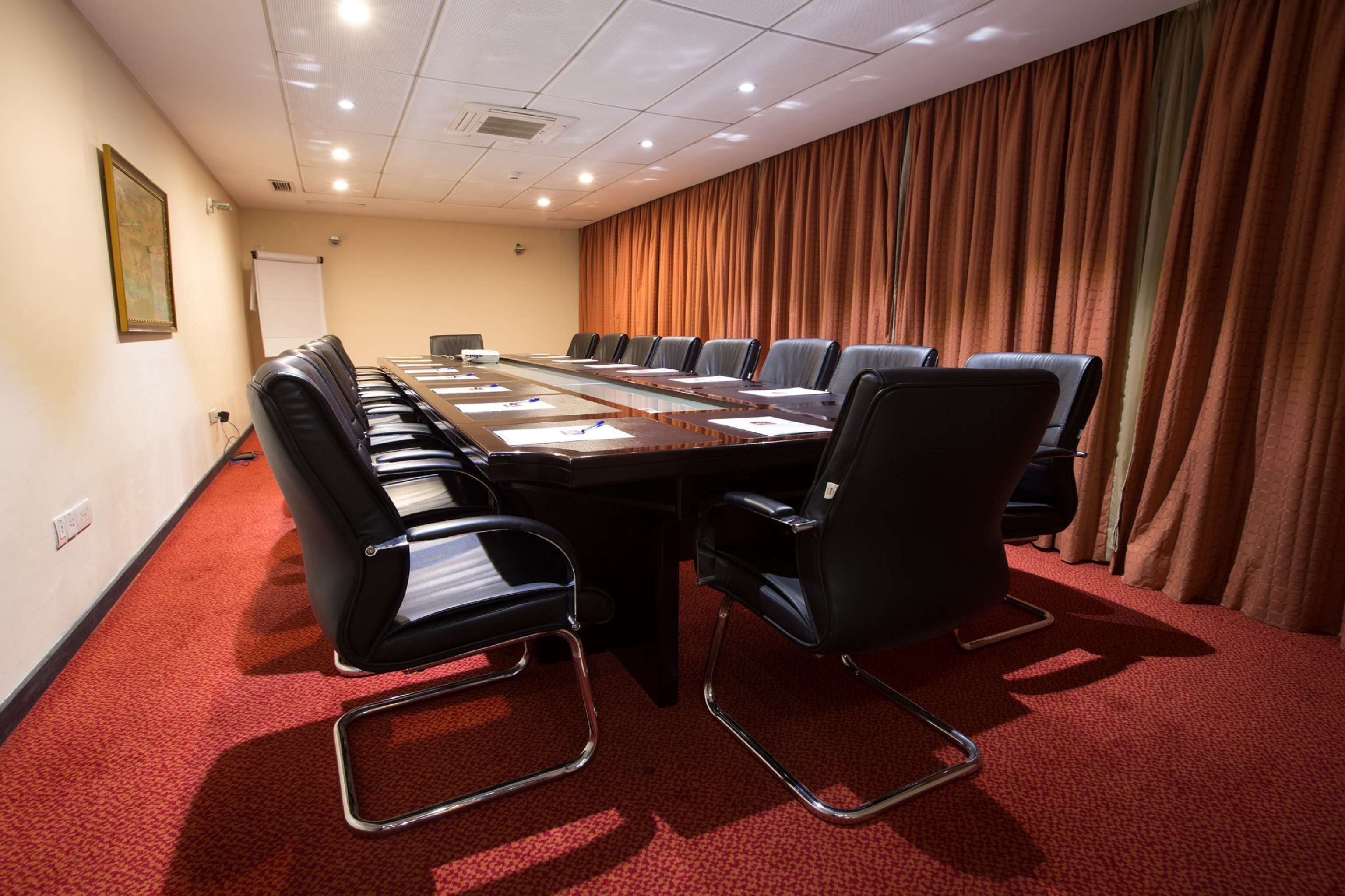 A conference room with a long table, black chairs, and a red carpet.