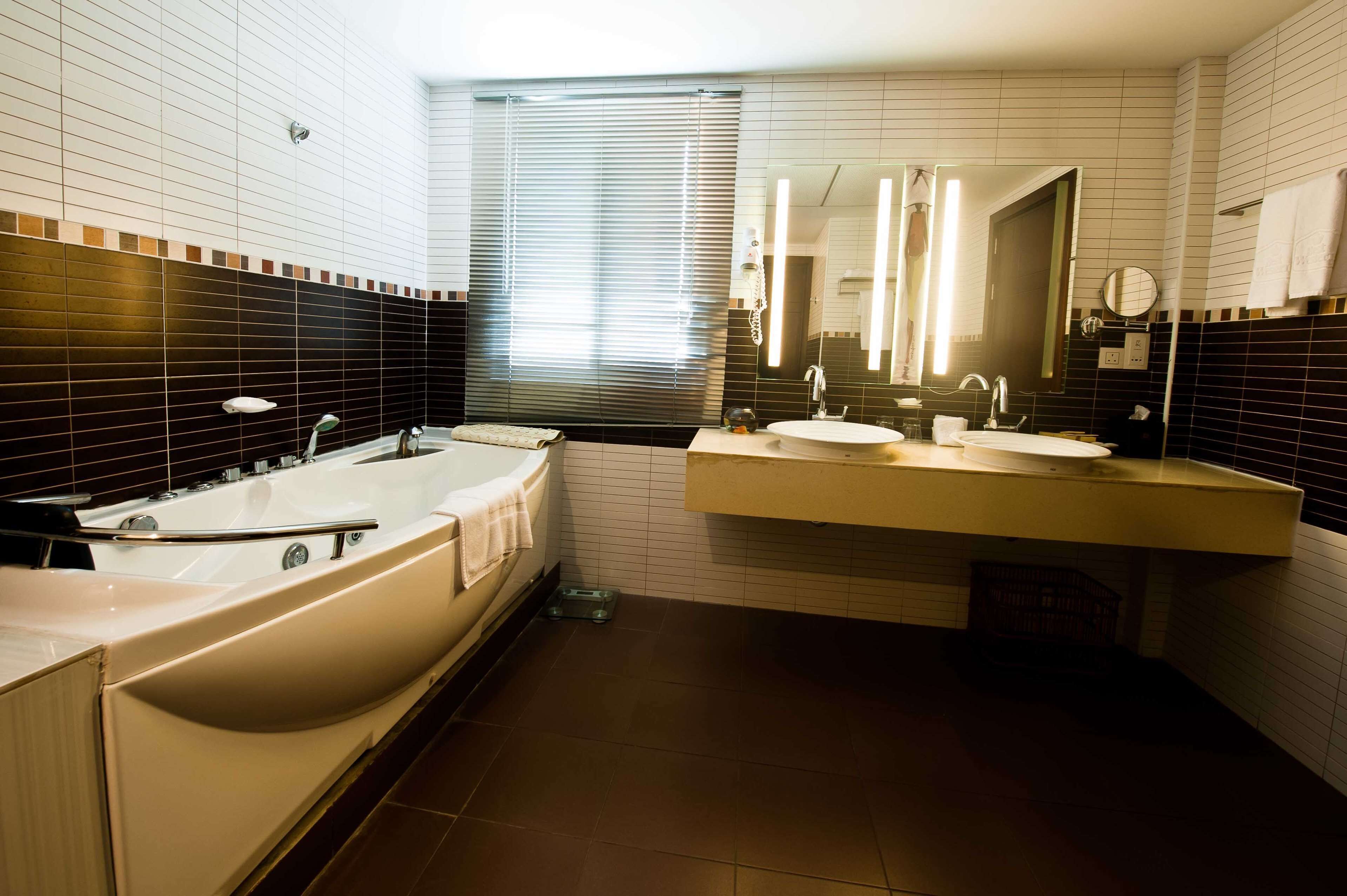 Un baño moderno con bañera, dos lavabos y un espejo grande.