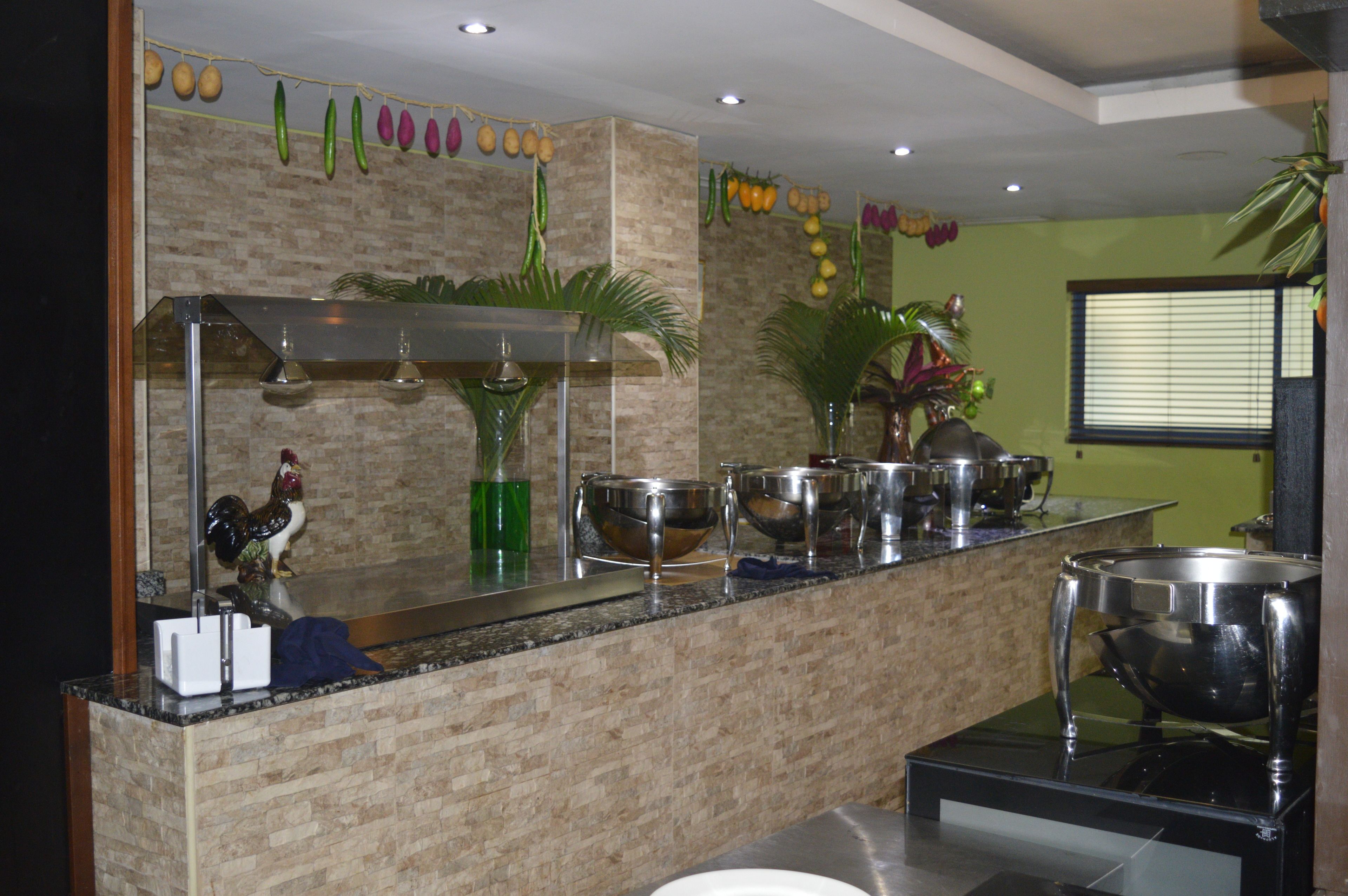 A kitchen with a granite countertop, stainless steel appliances, and decorative items including a rooster figurine and hanging fruits.