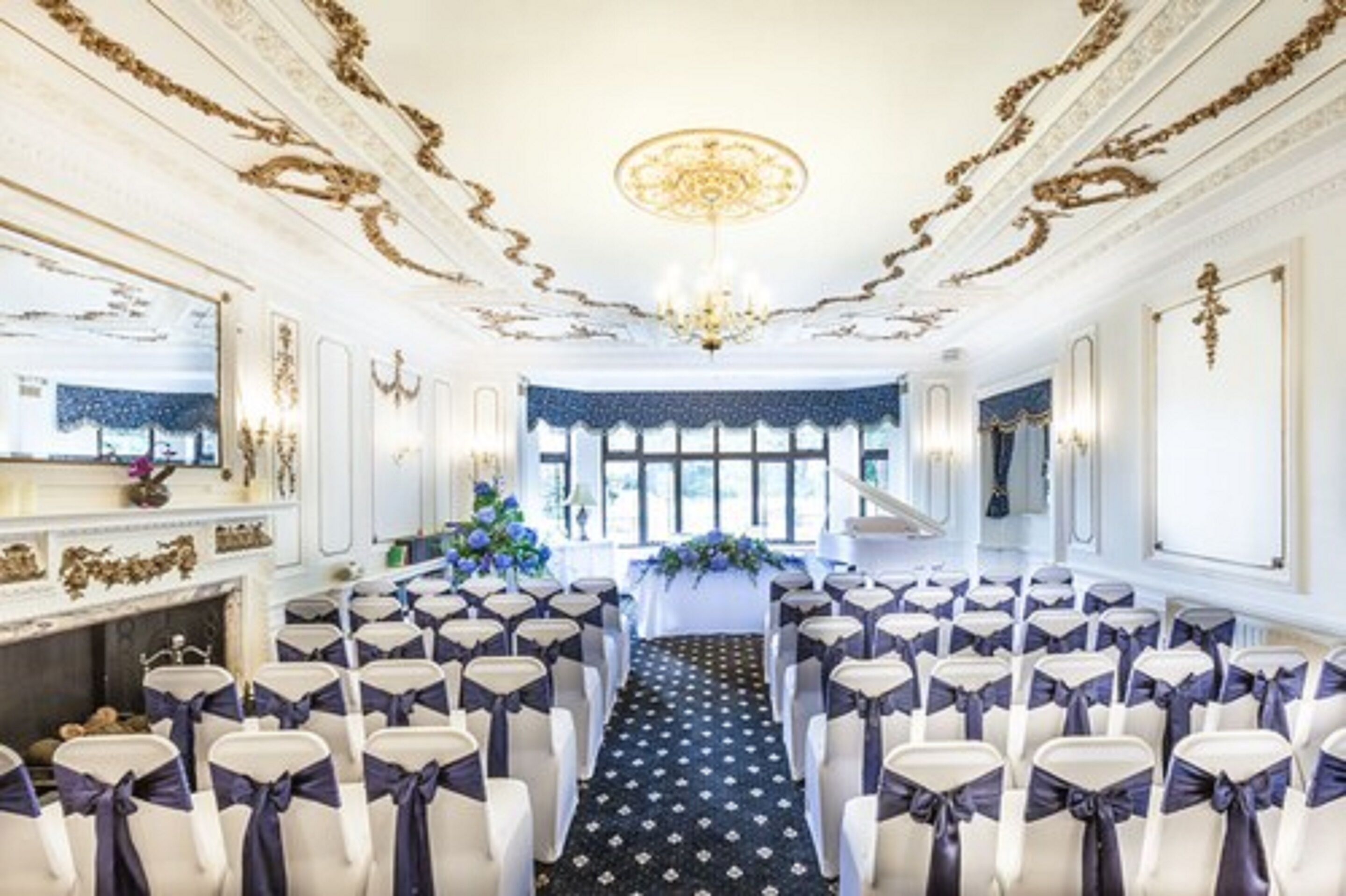 A formal event space with rows of chairs, a central aisle, and a chandelier.