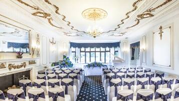 A formal event space with rows of chairs, a central aisle, and a chandelier.