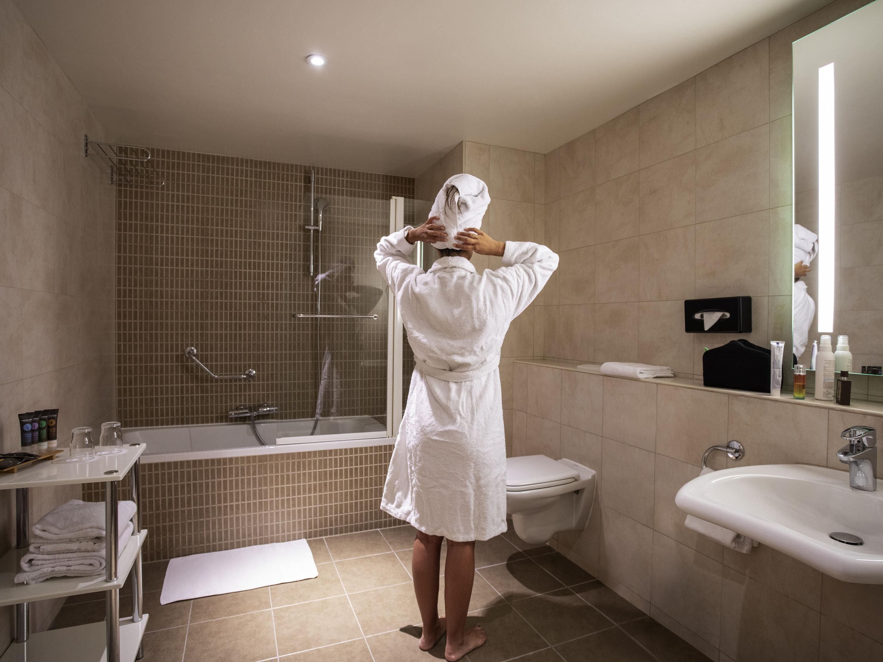 Un baño moderno con bañera, inodoro, lavamanos y mampara de vidrio.