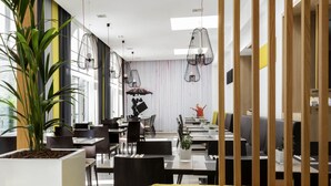 A modern dining area with high ceilings, pendant lighting, and a mix of seating arrangements. - Novotel Brussels Centre Midi Station (Brussels)