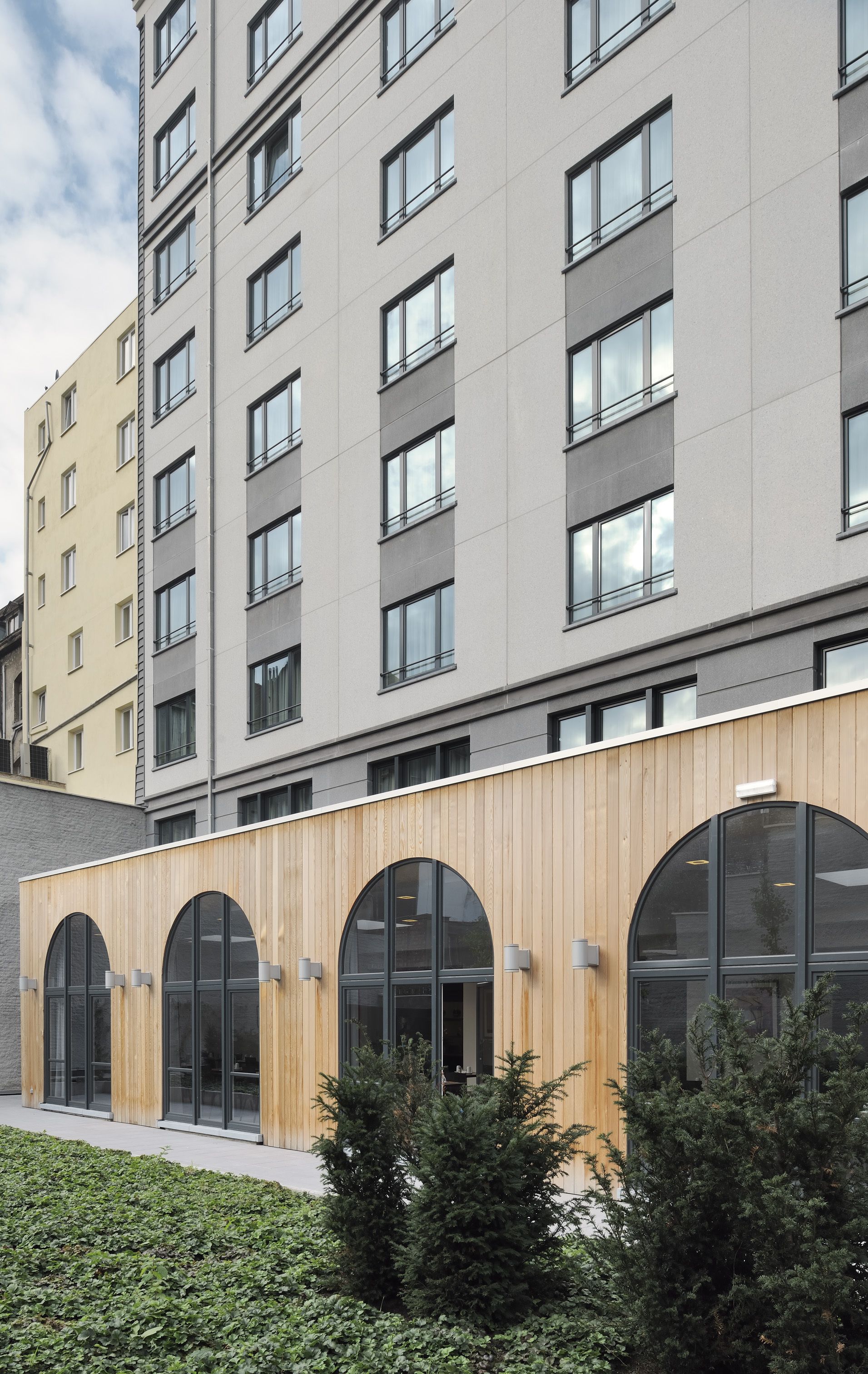 A multi-story building with a modern architectural design, featuring large windows and a wooden facade.