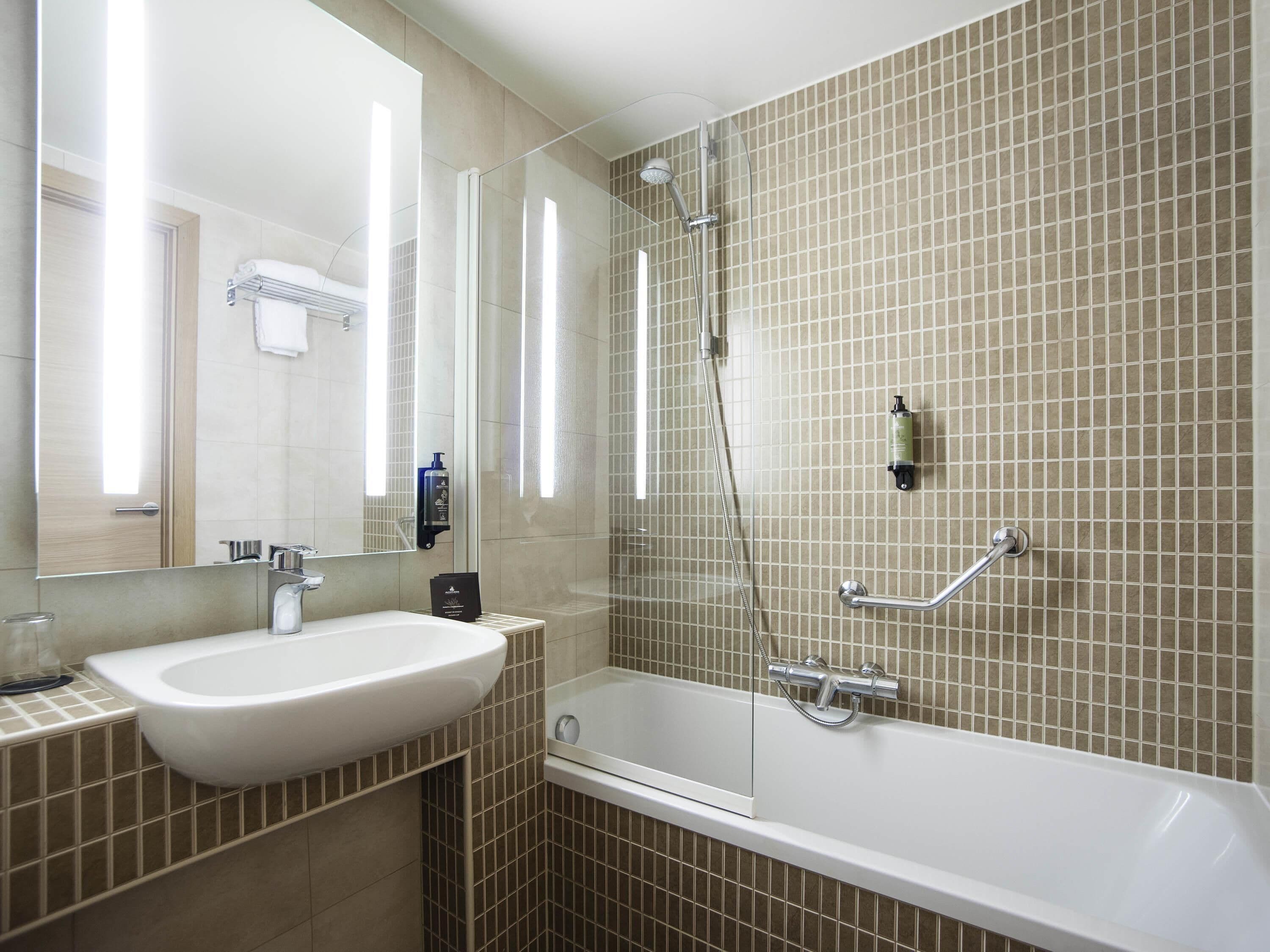 Une salle de bain moderne équipée d’une baignoire, d’un lavabo, d’un miroir et d’une douche.