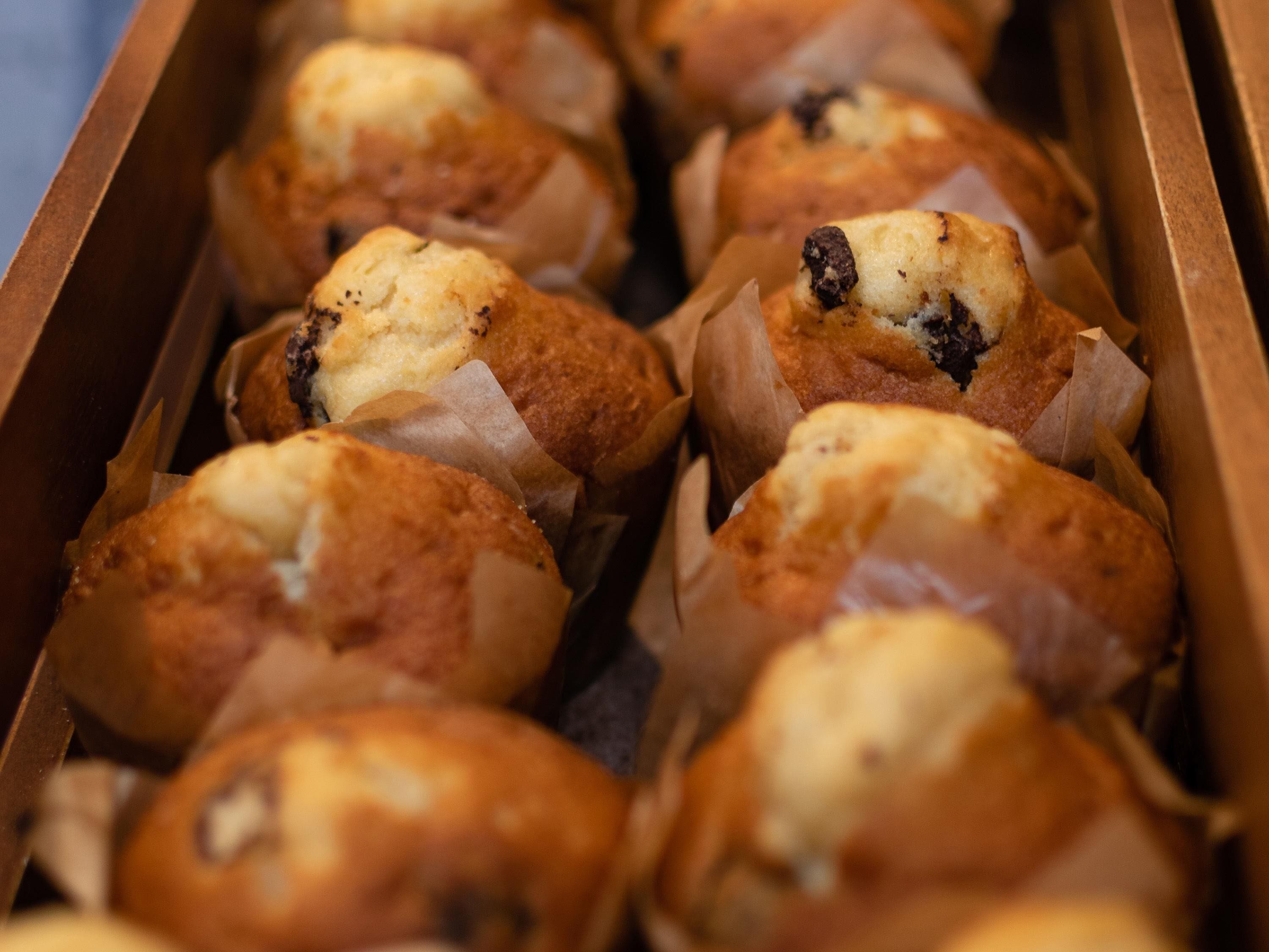 Een doos muffins met zichtbare chocoladestukjes en een goudbruine korst.