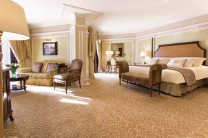 Una habitación de hotel con una cama grande, dos sillones, un sofá y un escritorio con una lámpara.