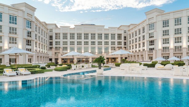 A hotel with a large pool, outdoor seating, and a well-maintained garden. - The Regency Hotel, Kuwait (Salmiya)