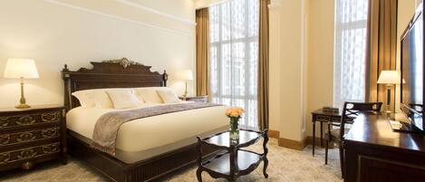 A hotel room with a large bed, a nightstand, a desk, and a chair.