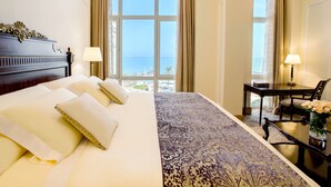 A hotel room with a large bed, a desk, two lamps, and a view of the sea. - The Regency Hotel, Kuwait (Salmiya)