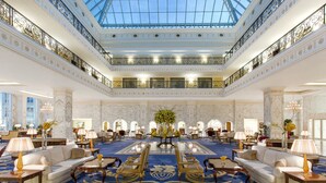 A grand hotel lobby with a high ceiling, marble walls, and a central floral arrangement. - The Regency Hotel, Kuwait (Salmiya)