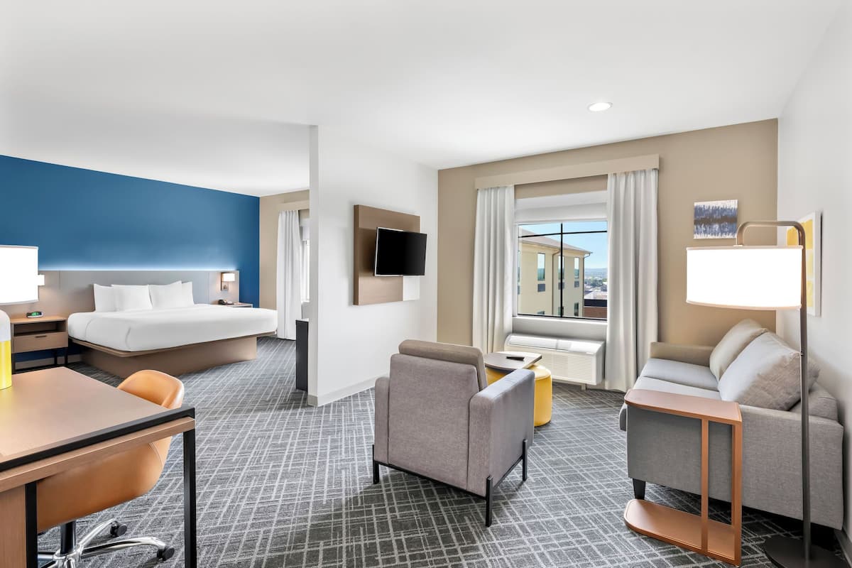 A hotel room with a bed, a desk, a sofa, and a TV.
