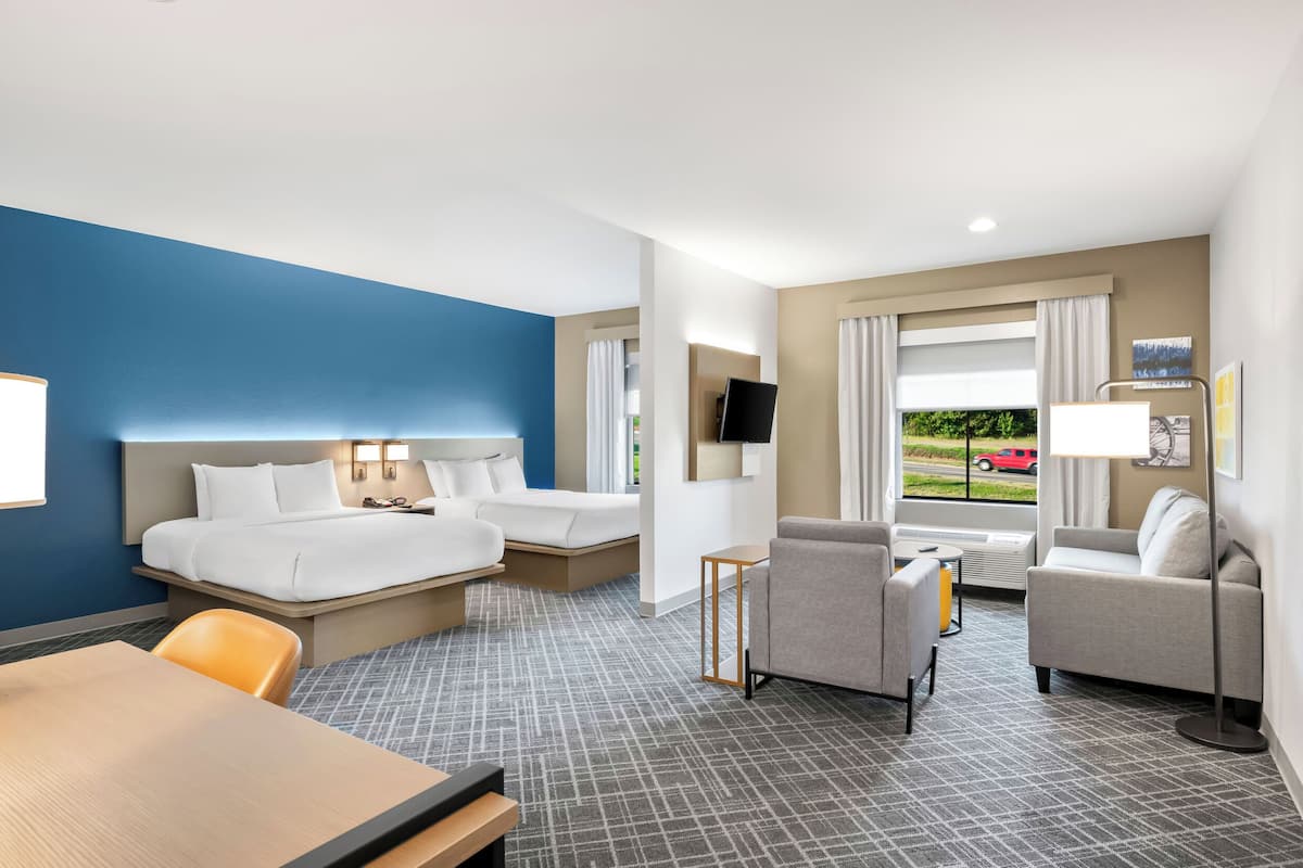A hotel room with a bed, two sofas, a desk, and a TV.