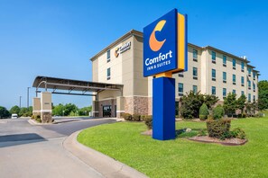 Un hotel Comfort Inn & Suites con entrada despejada, pasillo cubierto y jardines bien cuidados.