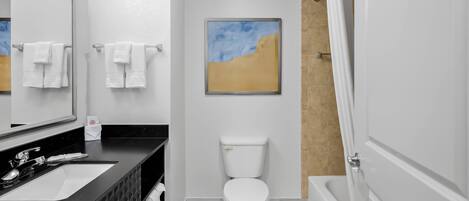 A modern bathroom with a black sink, white toilet, and a shower area.