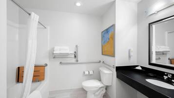 A modern bathroom with a white toilet, a black sink, and a shower with a white curtain.