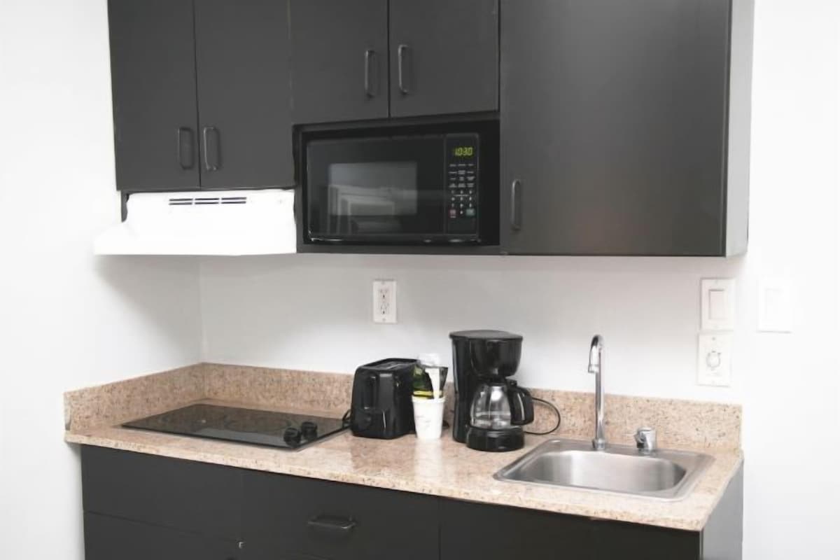 A kitchenette with a microwave, toaster, coffee maker, and sink.