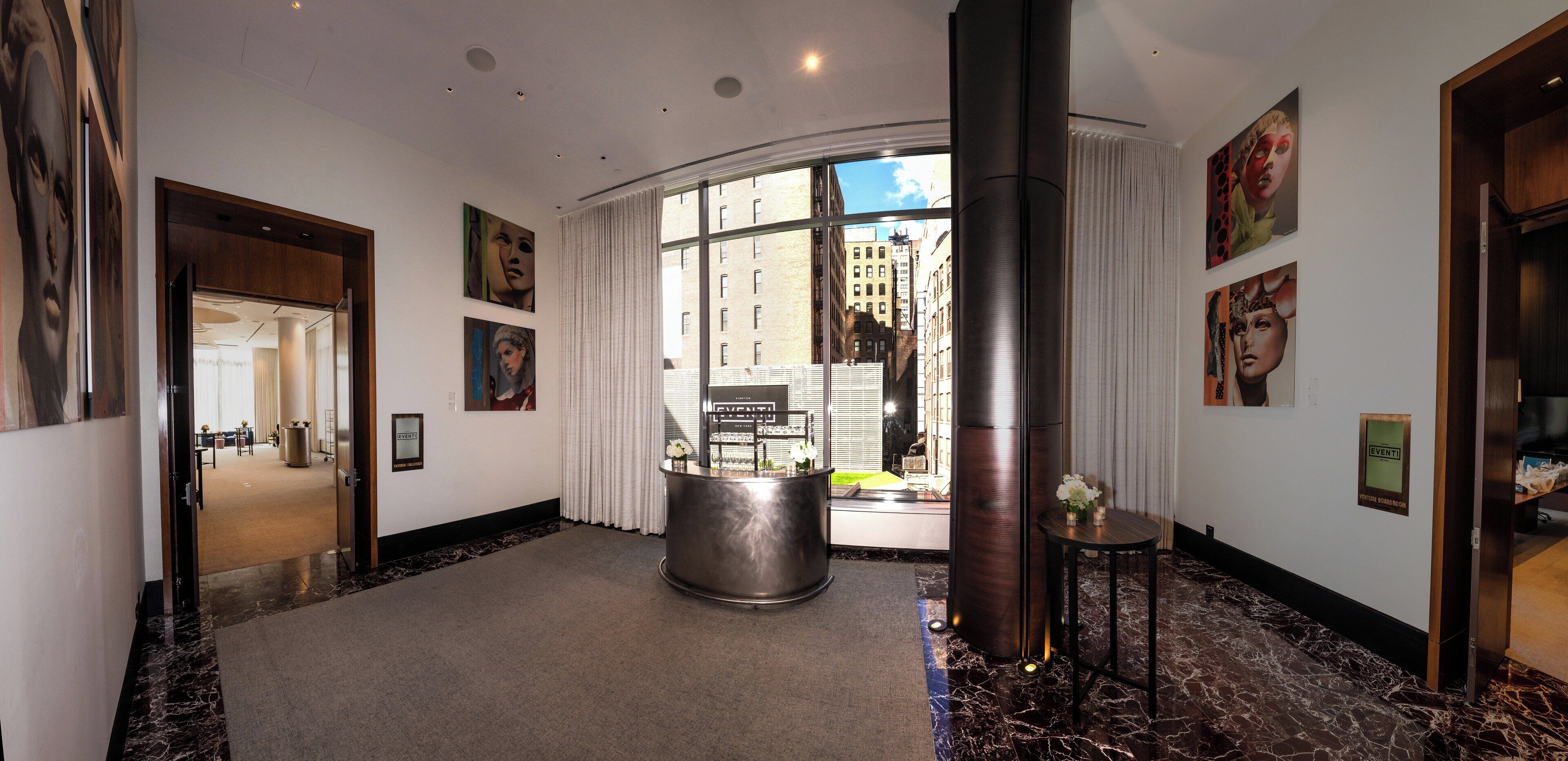 A hotel lobby with a marble floor, a reception desk, a large window with a city view, and artwork on the walls.