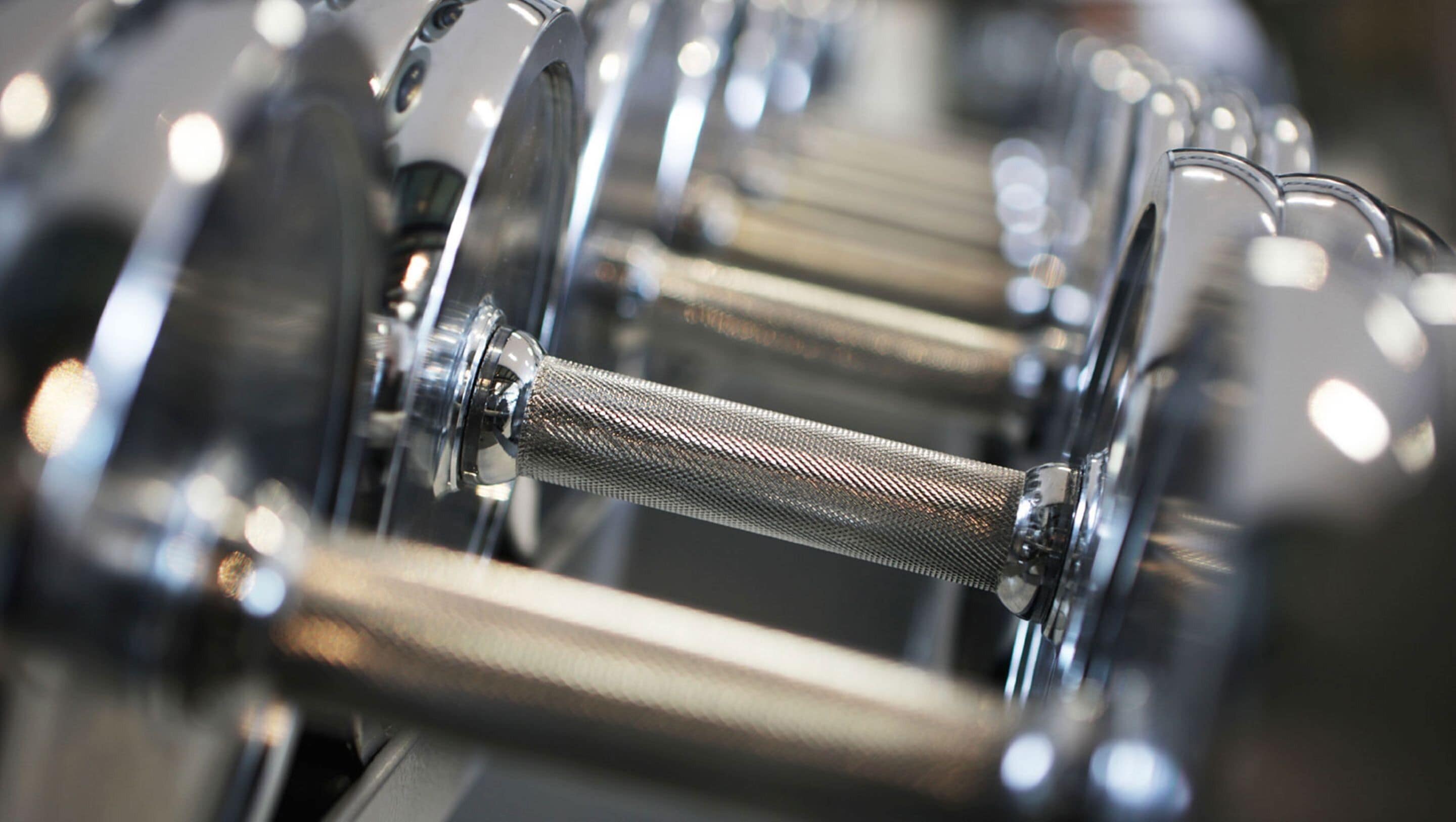 A close-up of a metallic dumbbell with a textured grip.