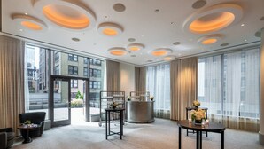 A hotel room with large windows, a round table with candles, a bar area, and a seating area with a chair and a small table. - Kimpton Hotel Eventi by IHG (New York)