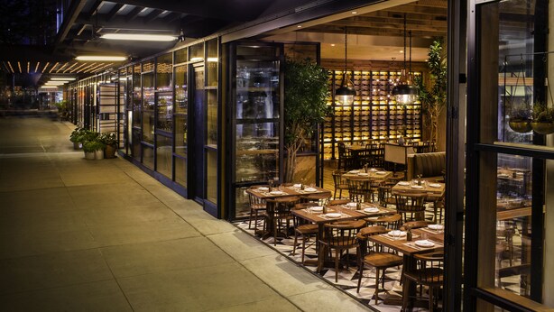 Un restaurant doté d’une terrasse, de grandes fenêtres et d’un mur intérieur en briques.