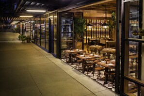 Un restaurante con terraza, amplias ventanas y paredes interiores de ladrillo.