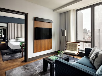 A cozy living room with a blue sofa, a coffee table with candles, a bookshelf, and a large TV. at Kimpton Hotel Eventi by IHG