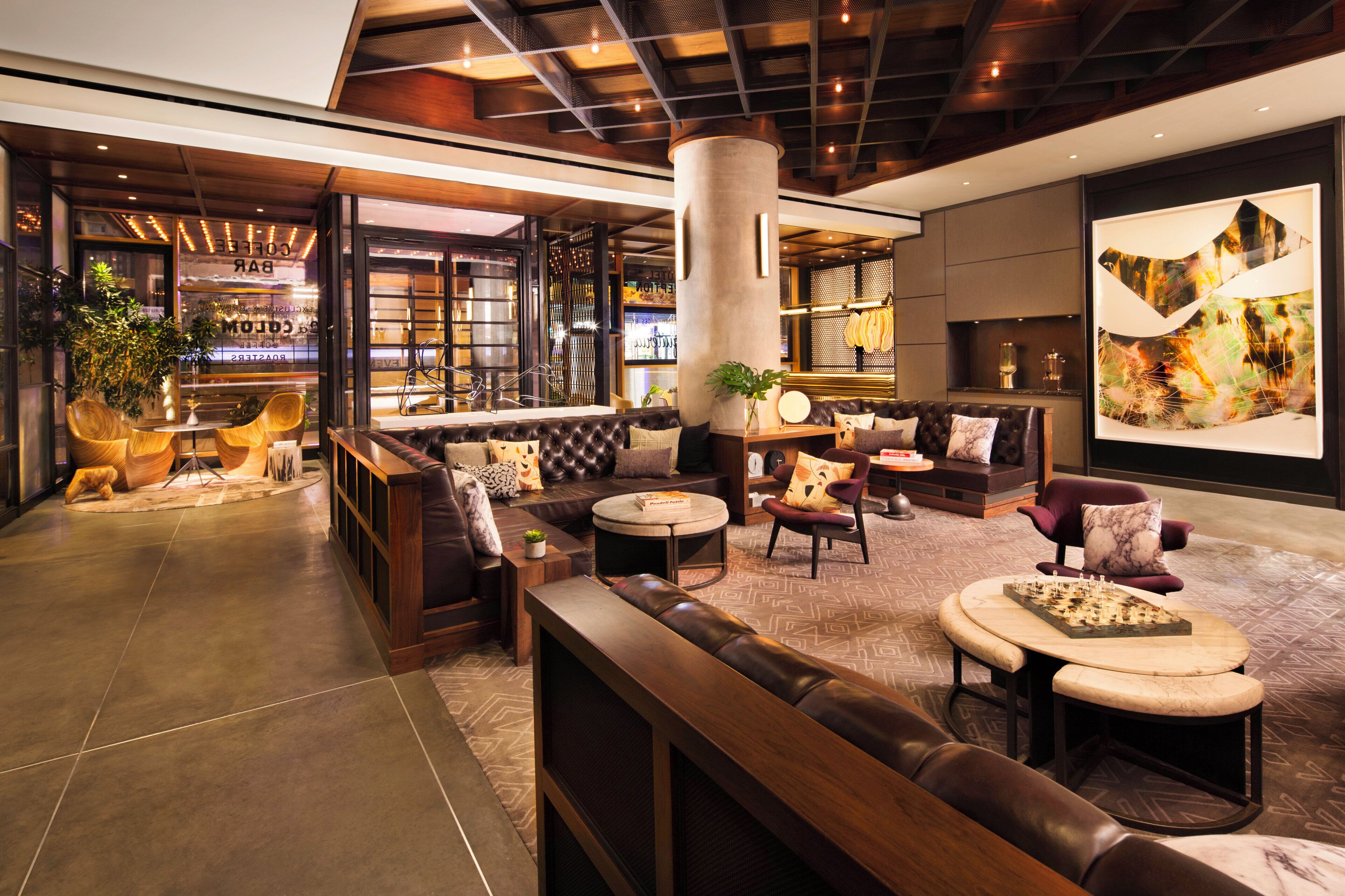 A modern lounge area with leather seating, a bar, and a large abstract painting.