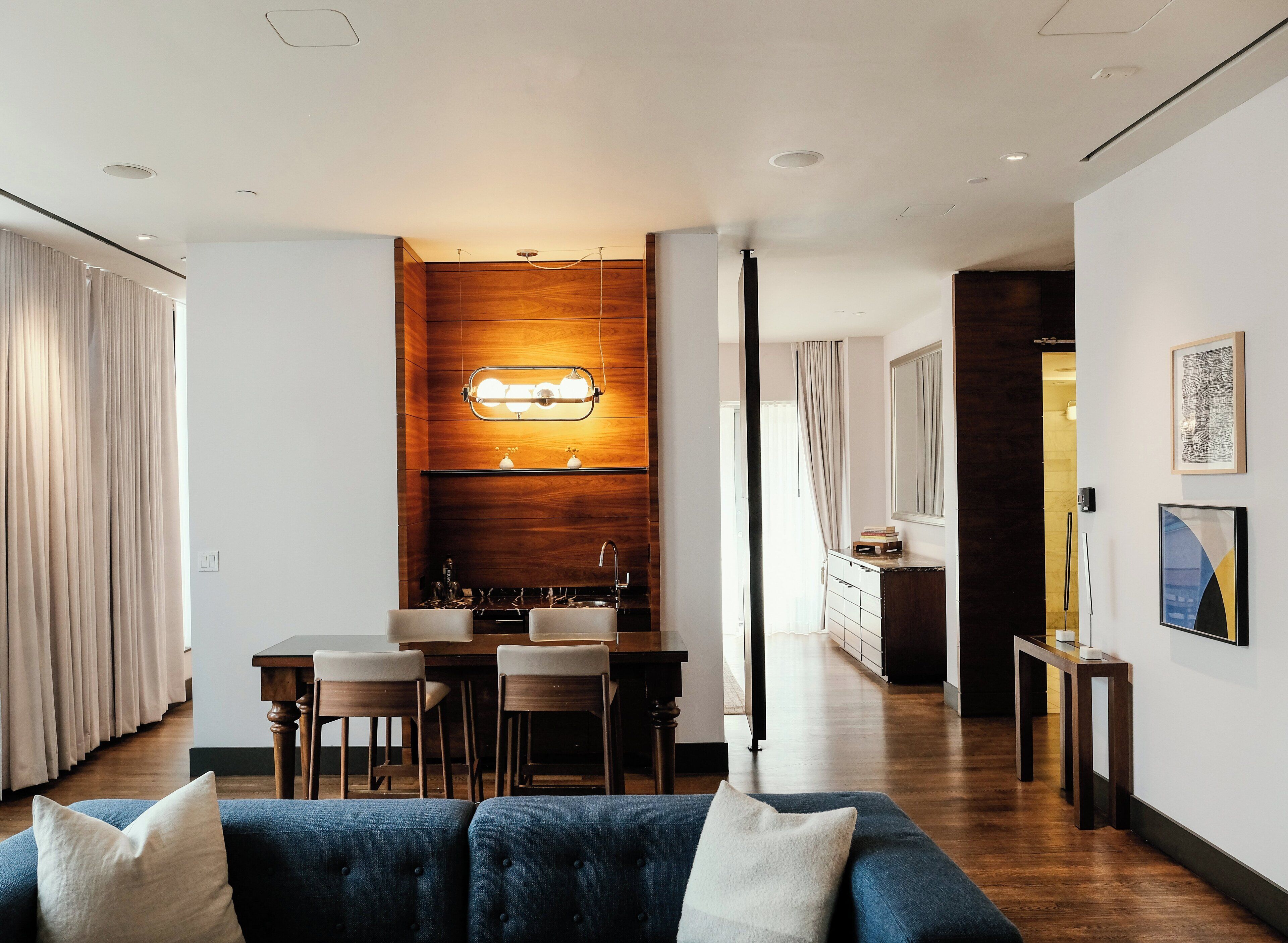 Ein modernes Wohnzimmer mit einem blauen Sofa, Holzakzenten und einem Essbereich mit Tisch und Stühlen.