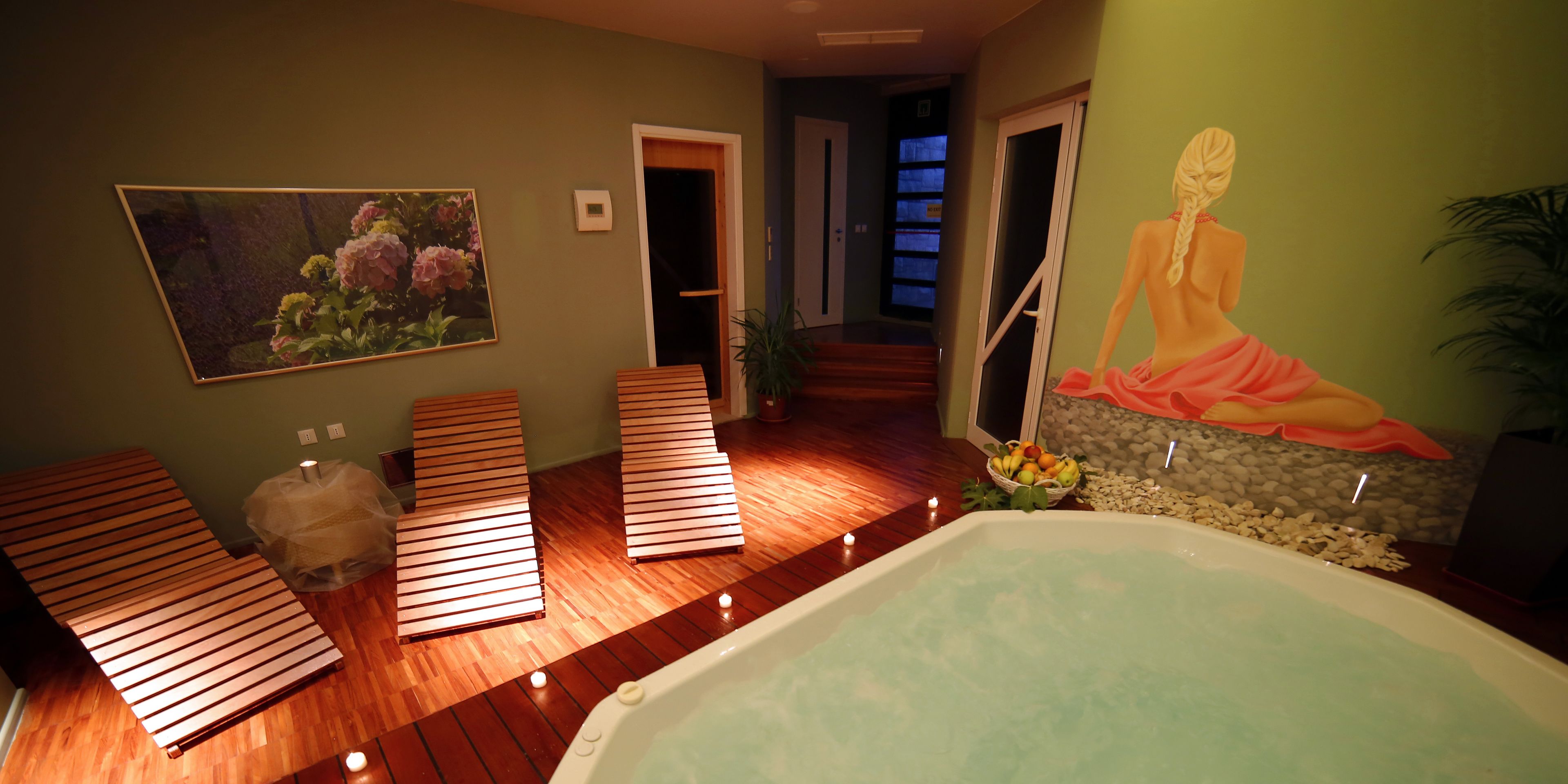 A spa room with a wooden floor, a large bathtub, and a painting of a woman in a pink dress.