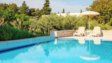 Alberca al aire libre, sombrillas en la alberca y camastros