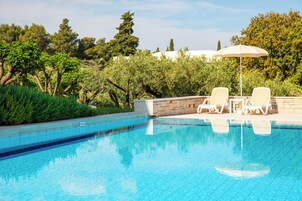 Una piscina al aire libre, sombrillas, sillones reclinables de piscina