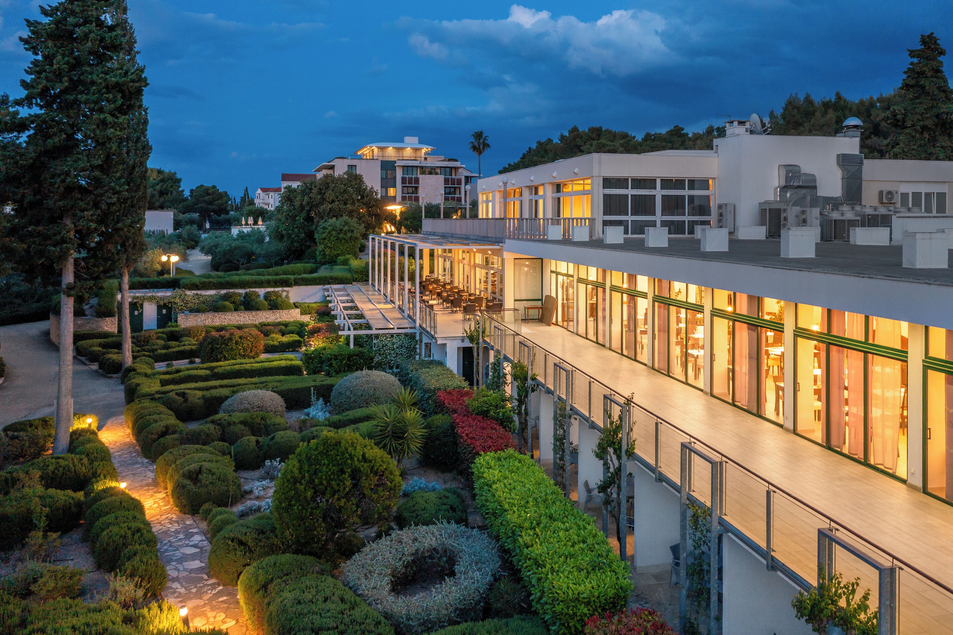Un hotel moderno con terraza en la azotea, jardines cuidados y vistas despejadas del entorno.