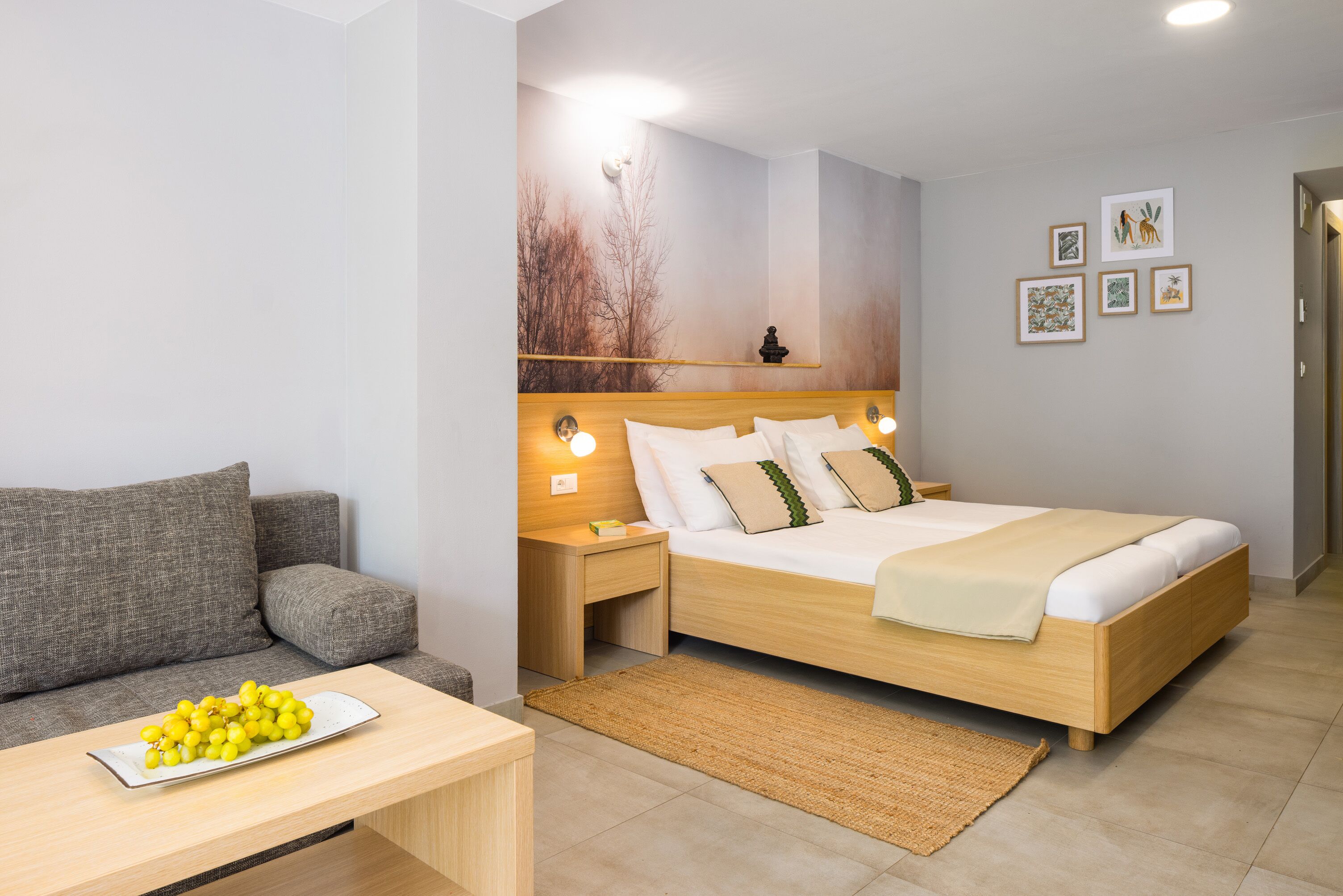 Une chambre à coucher moderne avec un lit en bois, un canapé gris et une table de chevet avec une lampe.