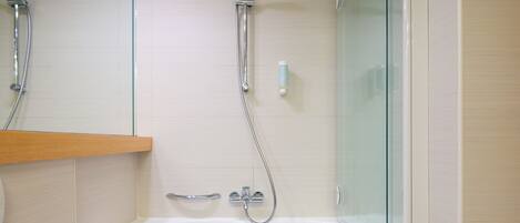 Un baño moderno con cabina de ducha de vidrio, bañera integrada y estante de madera.