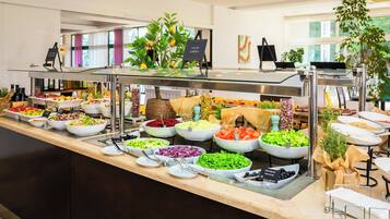 Un buffet proposant une variété de plats, notamment des salades, des fruits et des légumes.