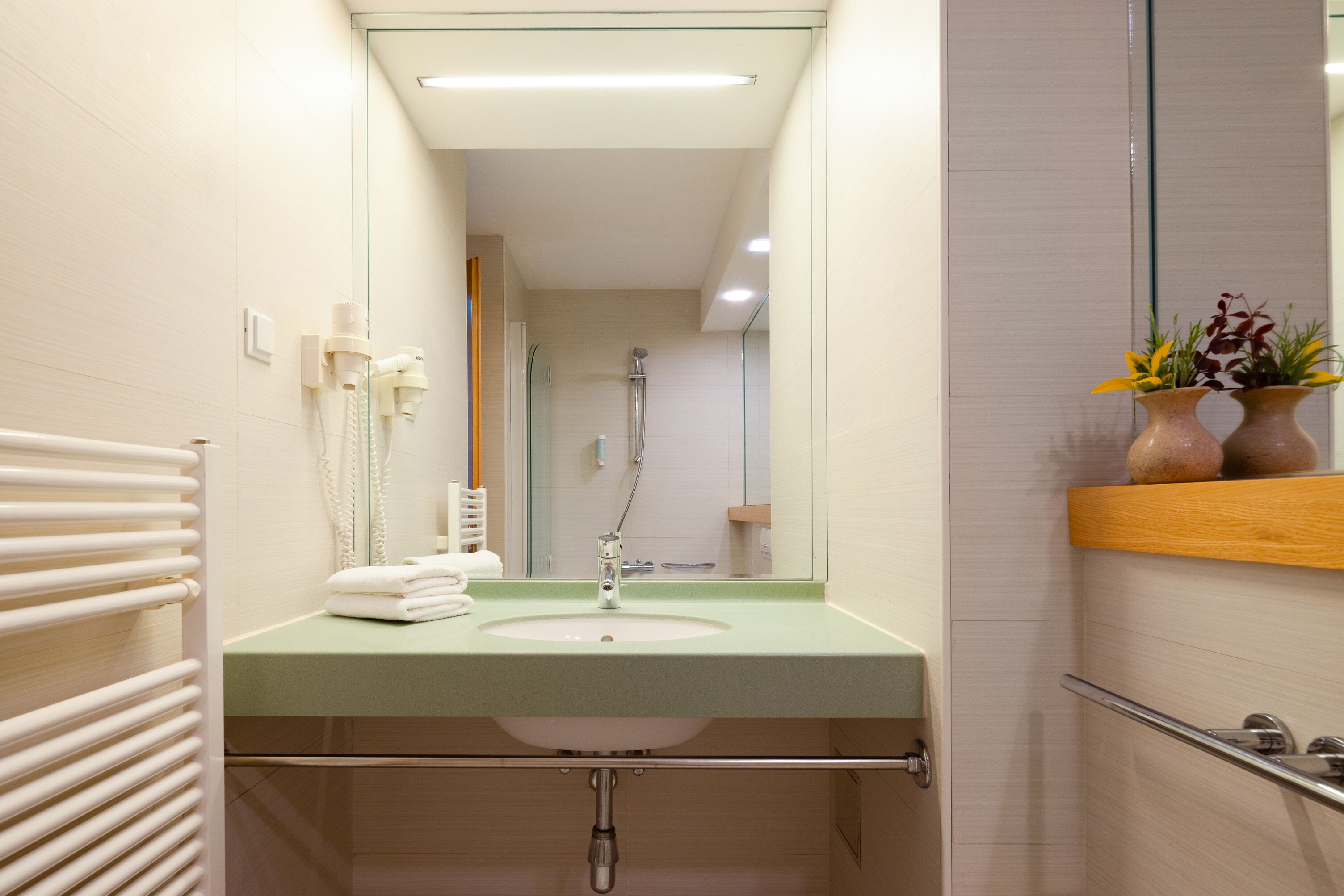 A modern bathroom with a green sink, a mirror, and a shower.