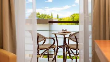A balcony with wicker chairs, a small round table, and an open book.
