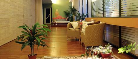 A room with a wooden floor, wicker furniture, and potted plants.