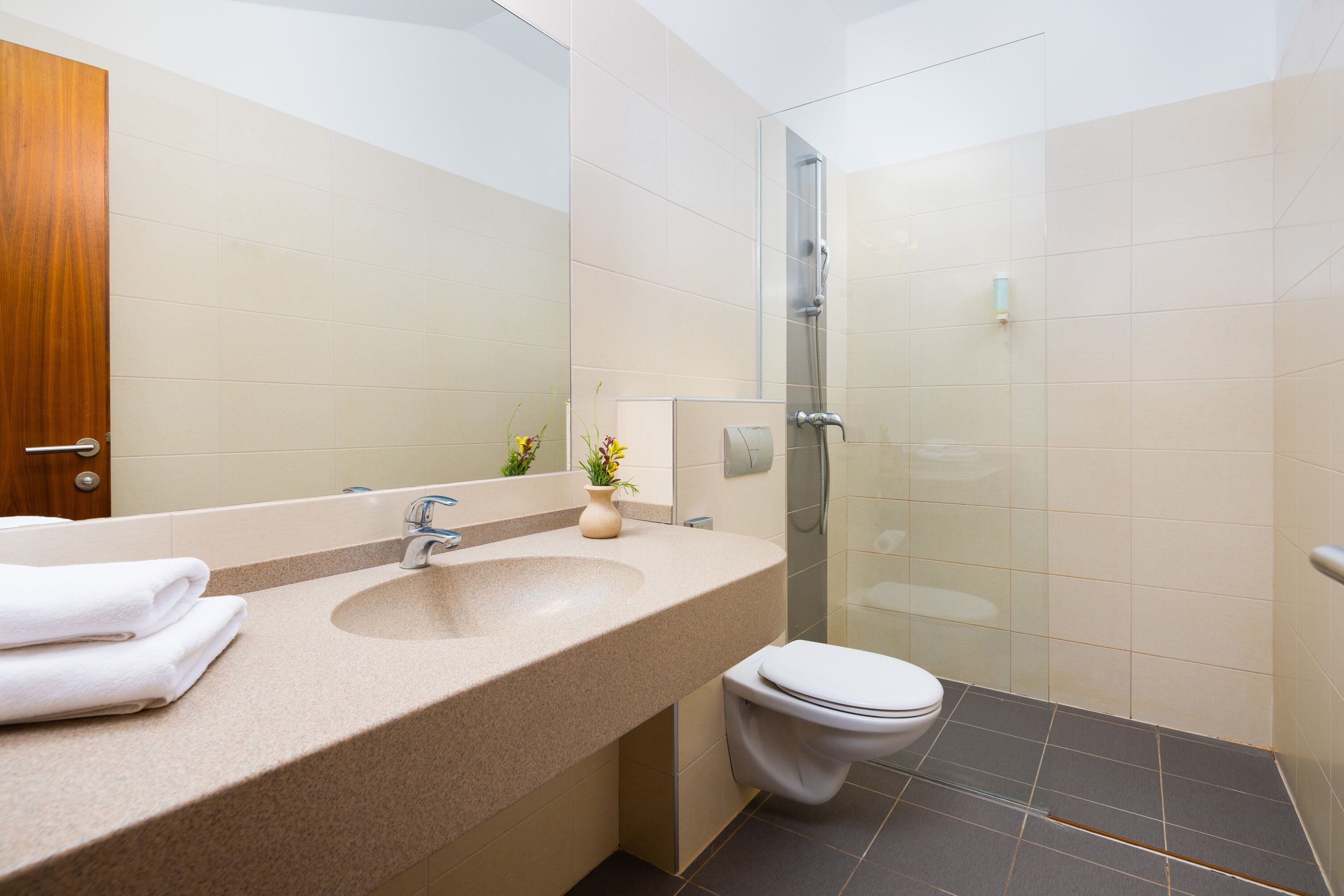 A bathroom with a sink, mirror, toilet, and shower.