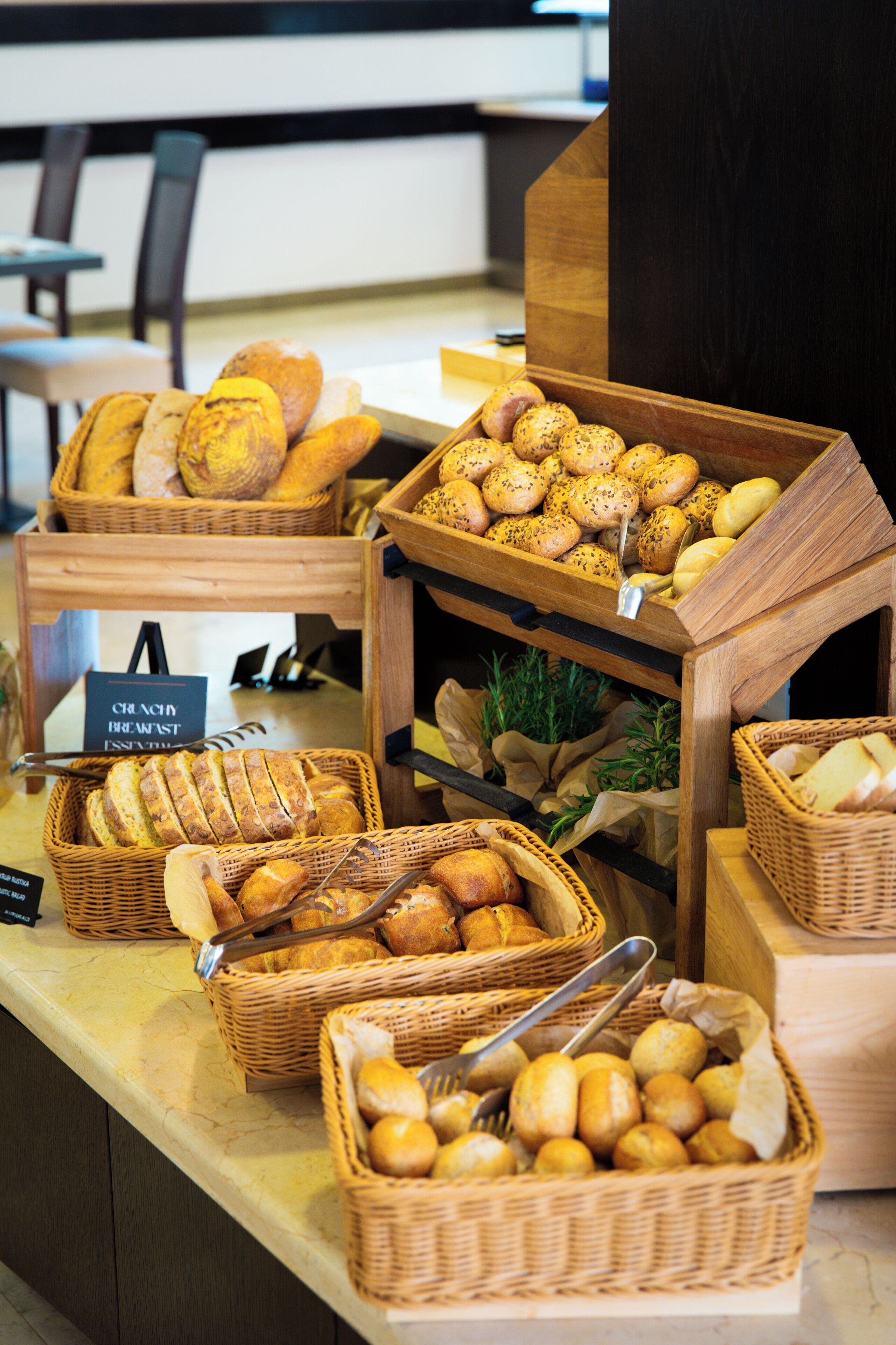 A breakfast buffet with various breads and pastries displayed in wicker baskets.