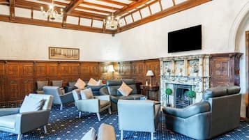 A spacious lounge with leather sofas, a fireplace, and a high wooden ceiling.